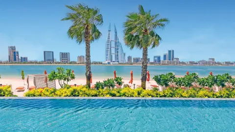 Blick auf die Skyline von Bahrain vom Pool aus, mit Strand und Palmen-placeholder